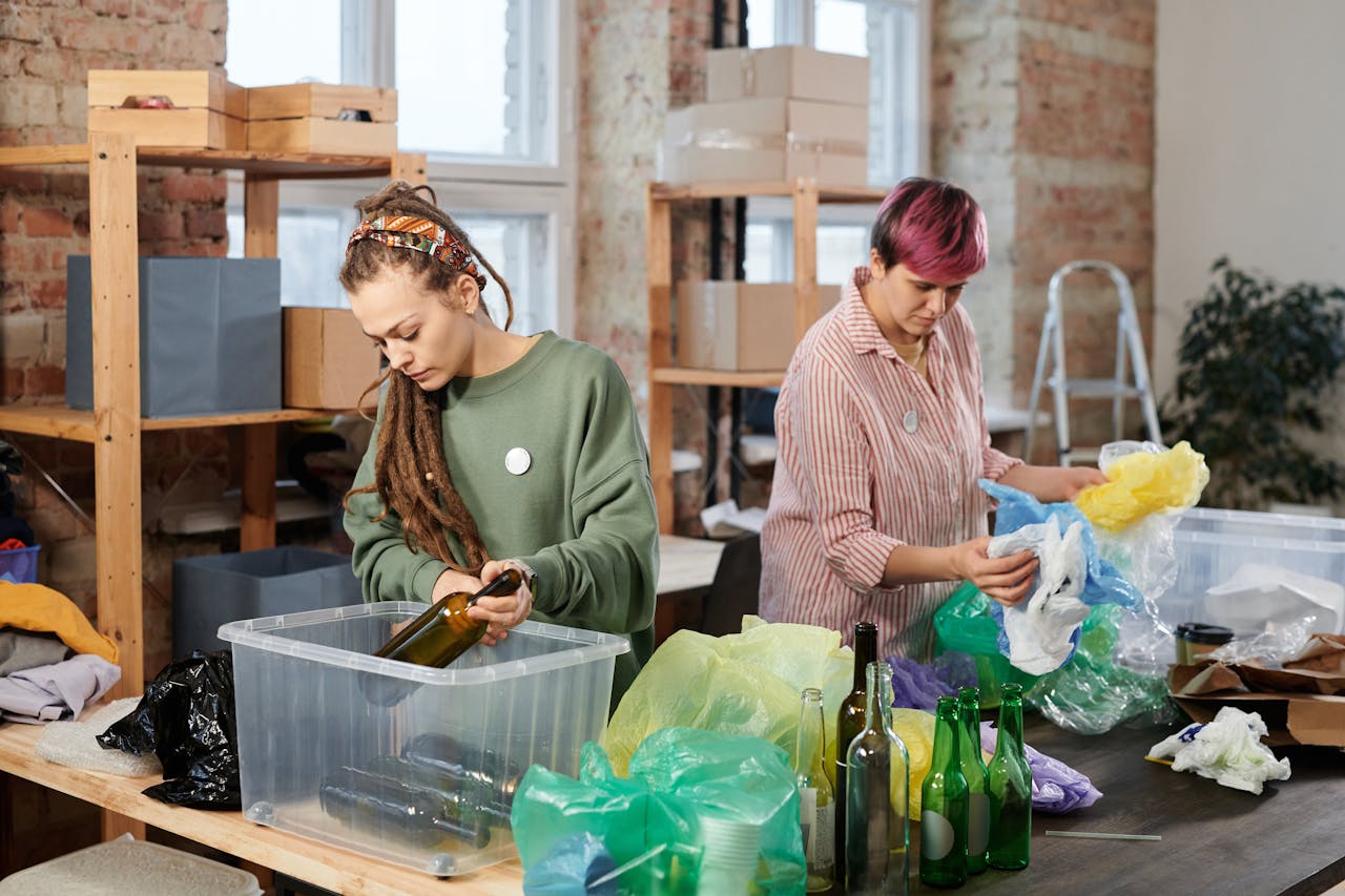 who-we-are Two women sorting glass and plastic waste in an indoor recycling center.